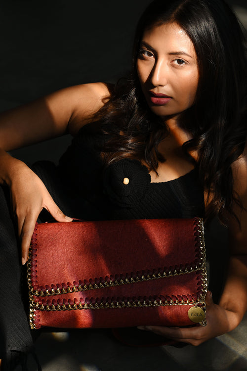 Female model holding a terracotta red bella handbag with a dark background